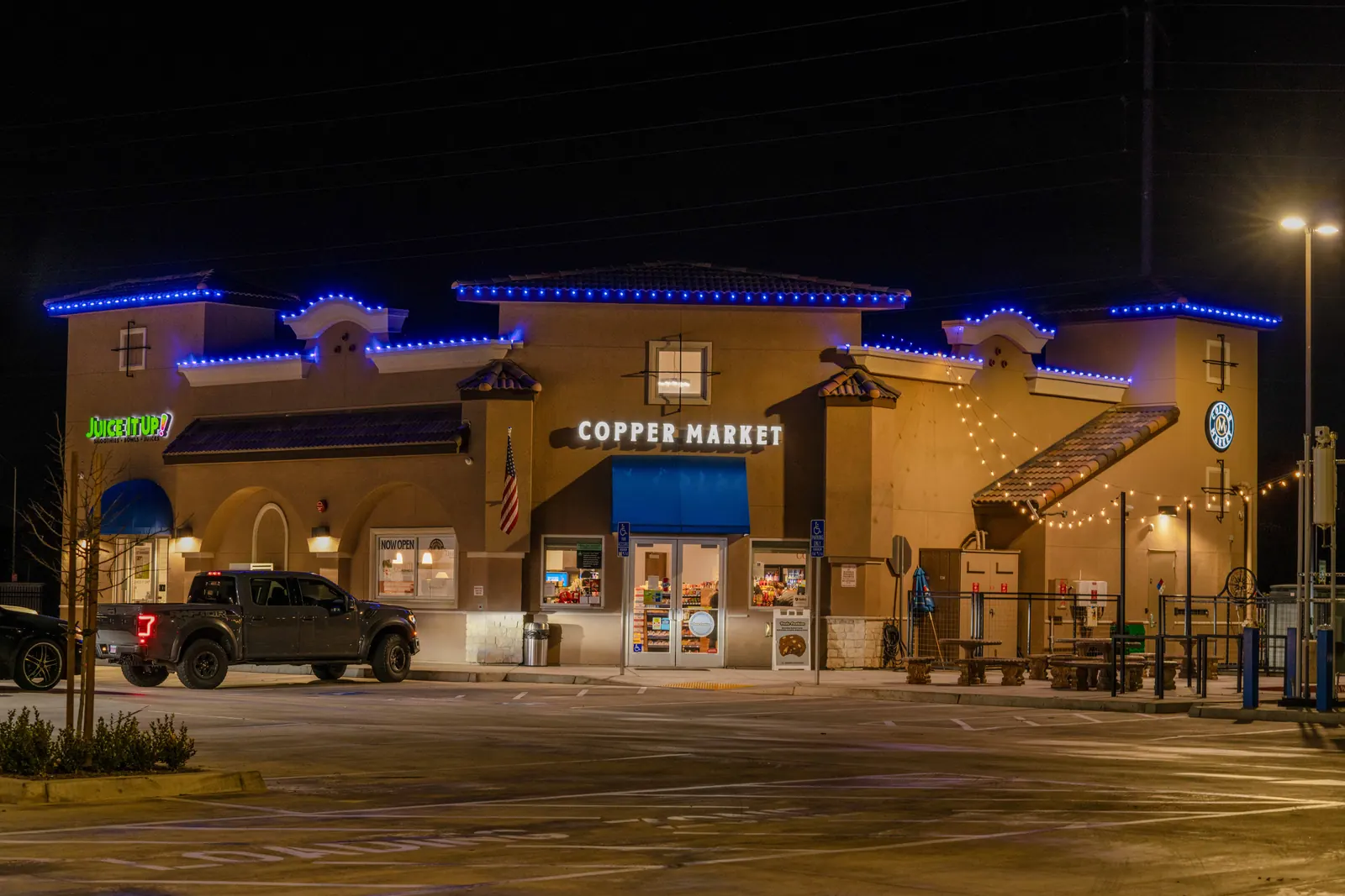 The same building at night with illuminated signs and blue LED roofline lighting
