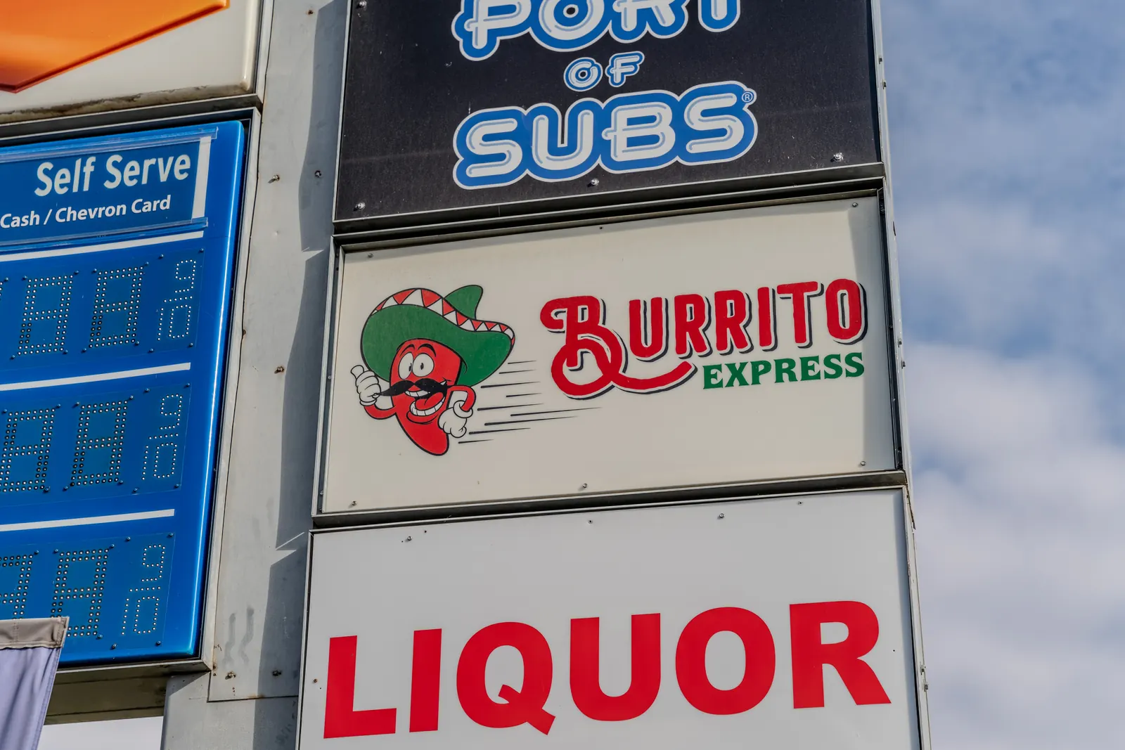 Port of Subs, Burrito Express and Liquor pan signs on a roadside sign structure