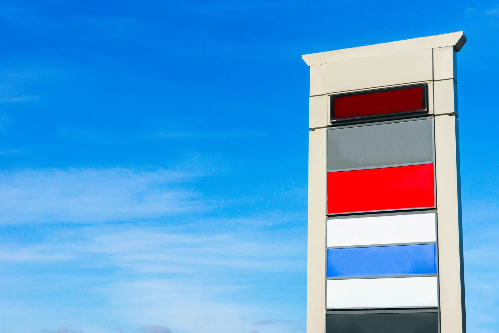 Multi-tenant pylon sign with colored tenant panels against a blue sky