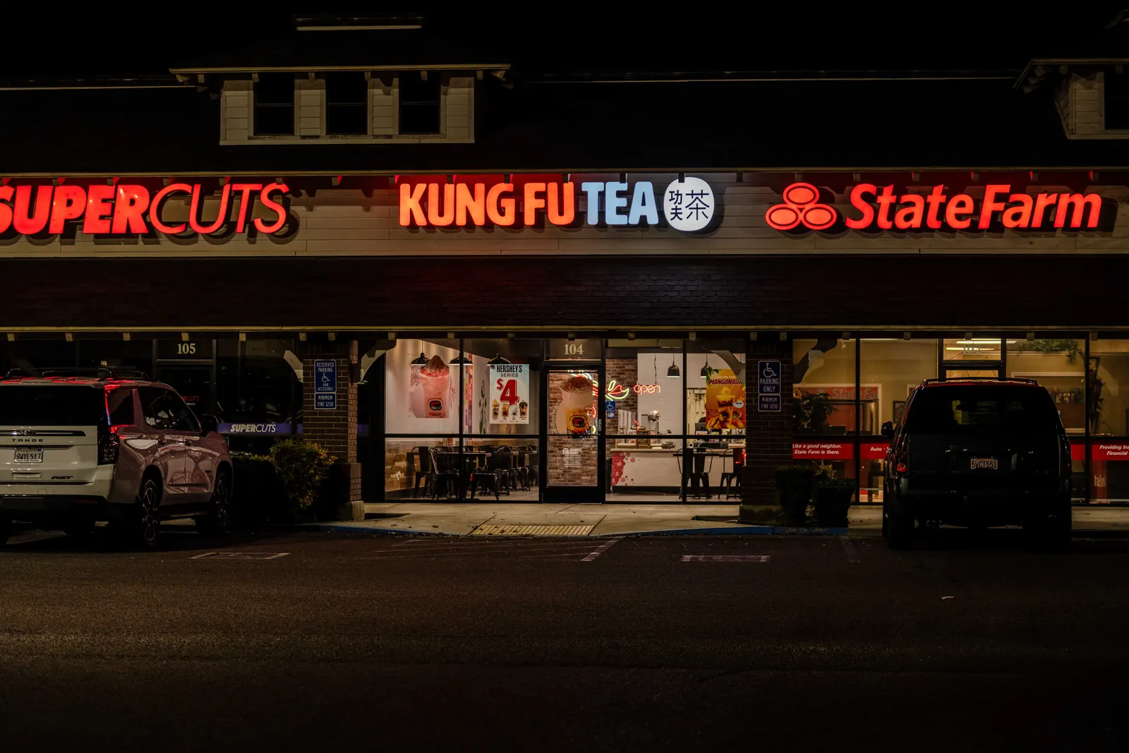Shopping center storefront signs lit up at night in Fresno
